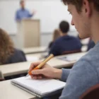 A student takes notes with Rifan Bamboo Twist Pens while listening to a lecturer in class.