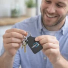Smiling man holding keys on a black King Leather Key Rings Square.