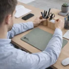Man organizing Axian Wireless Charging Mouse Mats and a notebook on his desk.