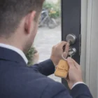 Man in a suit unlocking a door with an Alta Key Rings Rectangle labeled Seamans Bay Resort & Spa.