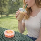 Woman enjoying iced coffee at a park with Silicone Straws In Logo Decorated Cases on the table.