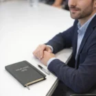 Man in suit at desk with Vennet Notebooks featuring YOUR LOGO HERE and a pen nearby.
