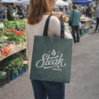 Woman at a farmers market with a Hiedi Heather Tote Bag labeled "Steak House".
