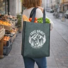 Woman with groceries in a Lisa Heather Tote Bag labeled "Free Spirit," walking in the city.