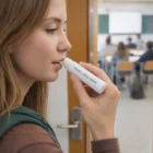Woman applies Flawless Kiss Lip Balm in a classroom; tube reads Your Logo Here.