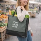 Woman at market holding a Vogue Shopper Heather Tote Bag with YOUR LOGO HERE printed on it.