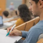 Student writing notes in class with a teal Arleth Custom Pen.