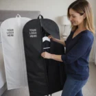 Woman unzipping black Lightweight Garment Bag; white bag behind, both show YOUR LOGO HERE.