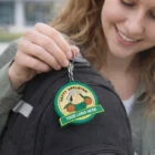 Woman attaches a Kiel Pvc Key Rings Large with custom logo to her black backpack.