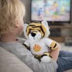 Child with Tiger Logo Printed Plush Toy watching TV in the living room.