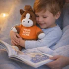 Smiling child hugs a Horse Personalised Plush Toy while reading a book.