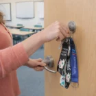 Person unlocking a classroom door with keys on Guinevere Key Rings and lanyards.