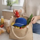 Placing a tomato in a jute bag with groceries, blue cap, and Class Cord Rope Caps on the counter.
