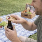 Man in Gedling uses Gedling Bottle Openers at a picnic with food and a wicker basket.