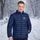 Man wears Sols Wilson Mens Puffer Jacket in snowy park with trees in the background.