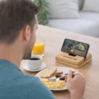 Man eating breakfast while watching camping video on Costwold Phone Stands.