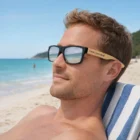 Man relaxing on a beach chair, wearing Martin Mirror Lens Sunglasses Bamboo with your logo.