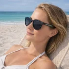 Woman relaxing by the sea in Calgary Sunglasses under a sunny sky.