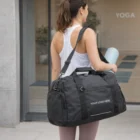 Woman with Swiss Peak RFID Sports Duffle Bag and yoga mat enters a building labeled YOGA.