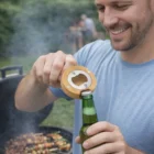 Man opens a beer with a Popfizz Bottle Opener at an outdoor barbecue grill.