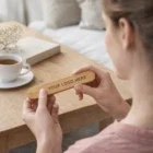 Woman holding a Palsy Bamboo Nail File near a table with coffee and a book.