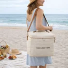 Woman with a Clanton Cooler Bag on the beach, picnic setup in the background.
