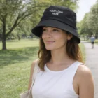 Woman in Norwalk park wears a Norwalk Leather Bucket Hat and a white tank top.