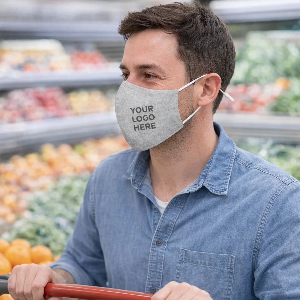 Man wears a Pyrenees Linen Face Mask with logo while shopping produce in a grocery store.
