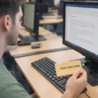 Man at computer plugs Fulton Credit Card 8Gb Flash Drive into monitor.