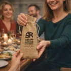 A woman gives a Costa Wine Drawstring Gift Bag at a dinner table.