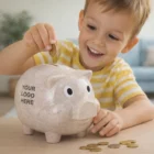 Smiling boy puts coins into a Wheat Husk Blend Piggy Bank with your logo on the side.