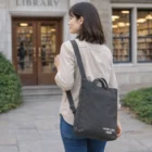 Woman with an Osprey Arcane Crossbody Bag stands outside a library entrance, facing away.