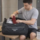 Man in gym clothes packs Osprey Daylite Duffle Bag with Your Logo Here on the side.