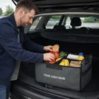 Man loads groceries into Car Trunk Organisers labeled Your Logo Here in a car's trunk.