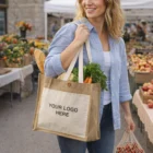Smiling woman at market holding Jute Tote Bags With Long Handles featuring Your Logo Here.
