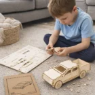Young boy assembling a Wooden UTE on the floor, instructions beside him.