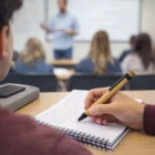 A student takes notes with Bamboo Eco Pens as a teacher speaks in the blurred background.