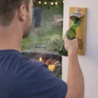 Man opening a beer by the grill with Magnetic Bamboo Openers.