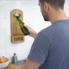 Man uses a Compact Wall Bottle Opener to open a bottle in his kitchen.