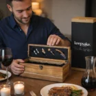 Man opens a Keepsake Wine Box Gift Set at a dinner table with food and wine.