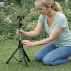 Woman sets up a Selfie Stick Tripod with phone holder in a garden.
