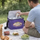 Man uses a Polar Beverage Cooler while enjoying a picnic with food on a blanket.