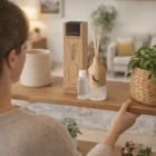 A person sets Wooden Reed Diffusers and a box on a wooden shelf in a cozy room.