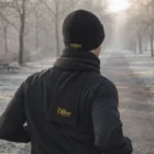 Person in Rib Knit Scarf And Beanie Set walks a frosty, tree-lined path with logos visible.