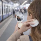 Person uses Travel Hairbrushes on a train platform for easy, on-the-go grooming.