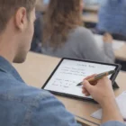 Person taking handwritten notes on a tablet with a Rhys Bamboo Stylus Pen during class.