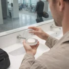 Man using Branded Soap Case to hold a round soap bar at an airport restroom sink.