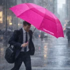 Man in suit walks in rain with a bright pink Hurricane Urban Diana Umbrella among others.