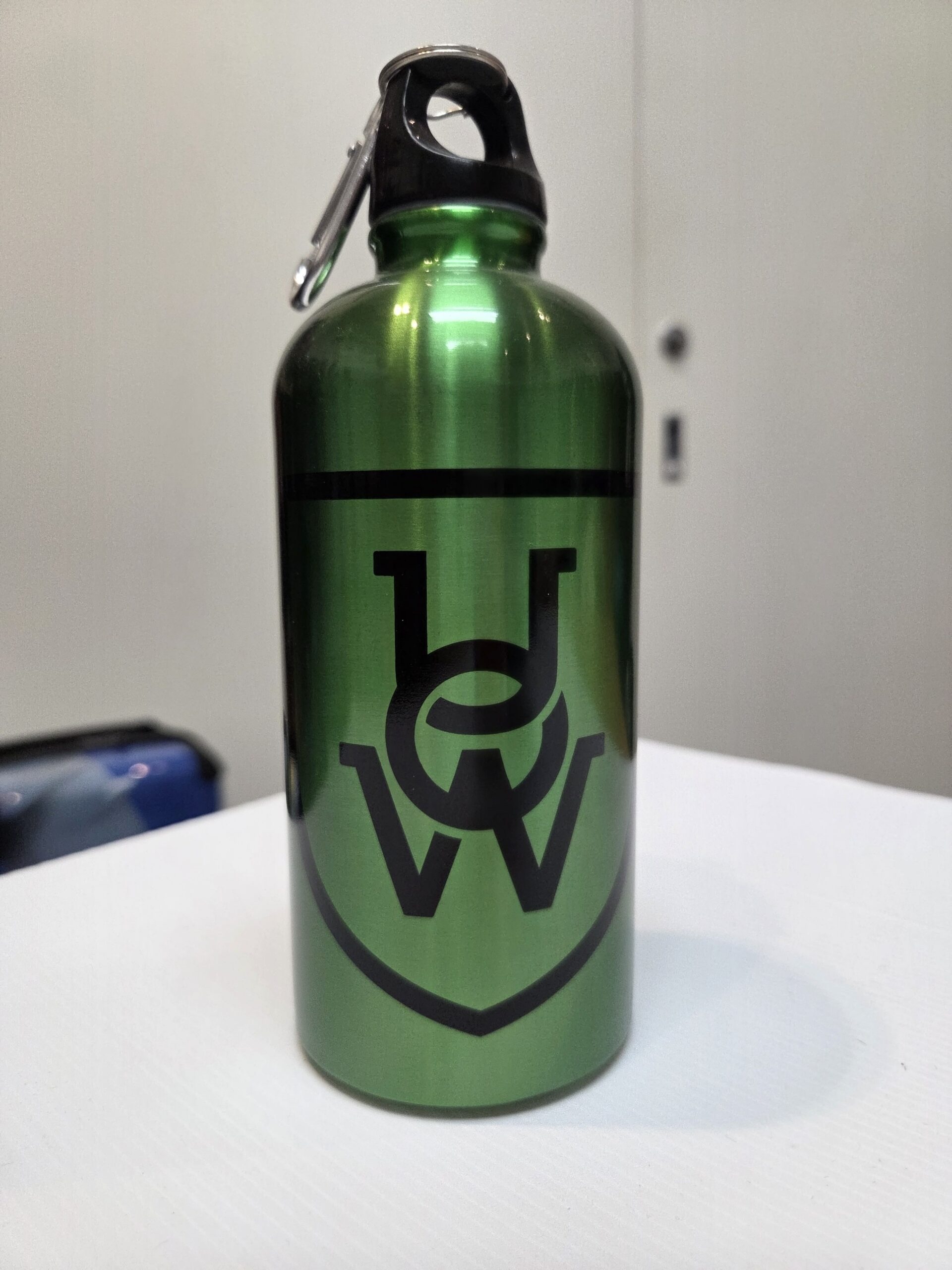 A green water bottle, best size bottles, with a black UCW logo and carabiner on the cap.