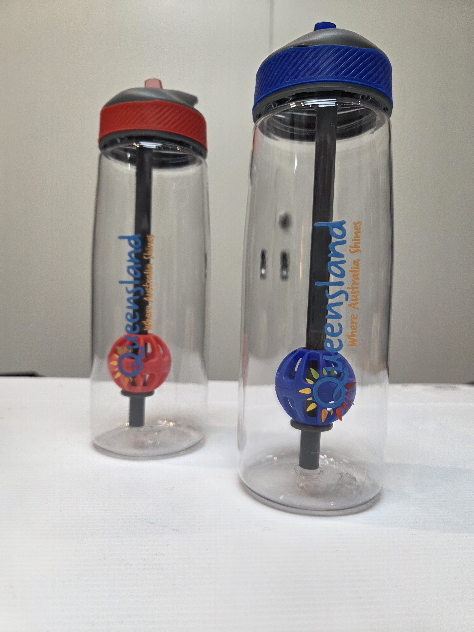 Two best size bottles with blue and red lids, straws, and colorful mixer balls inside.